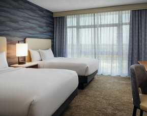 Guest room with two queen beds, modern amenities, and a comfortable atmosphere for families or groups at Embassy Suites By Hilton Charleston Airport Convention Center.