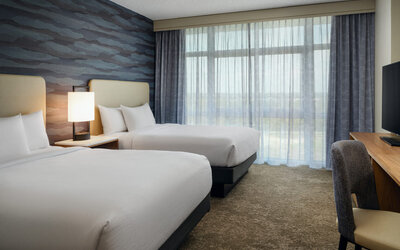 Guest room with two queen beds, modern amenities, and a comfortable atmosphere for families or groups at Embassy Suites By Hilton Charleston Airport Convention Center.