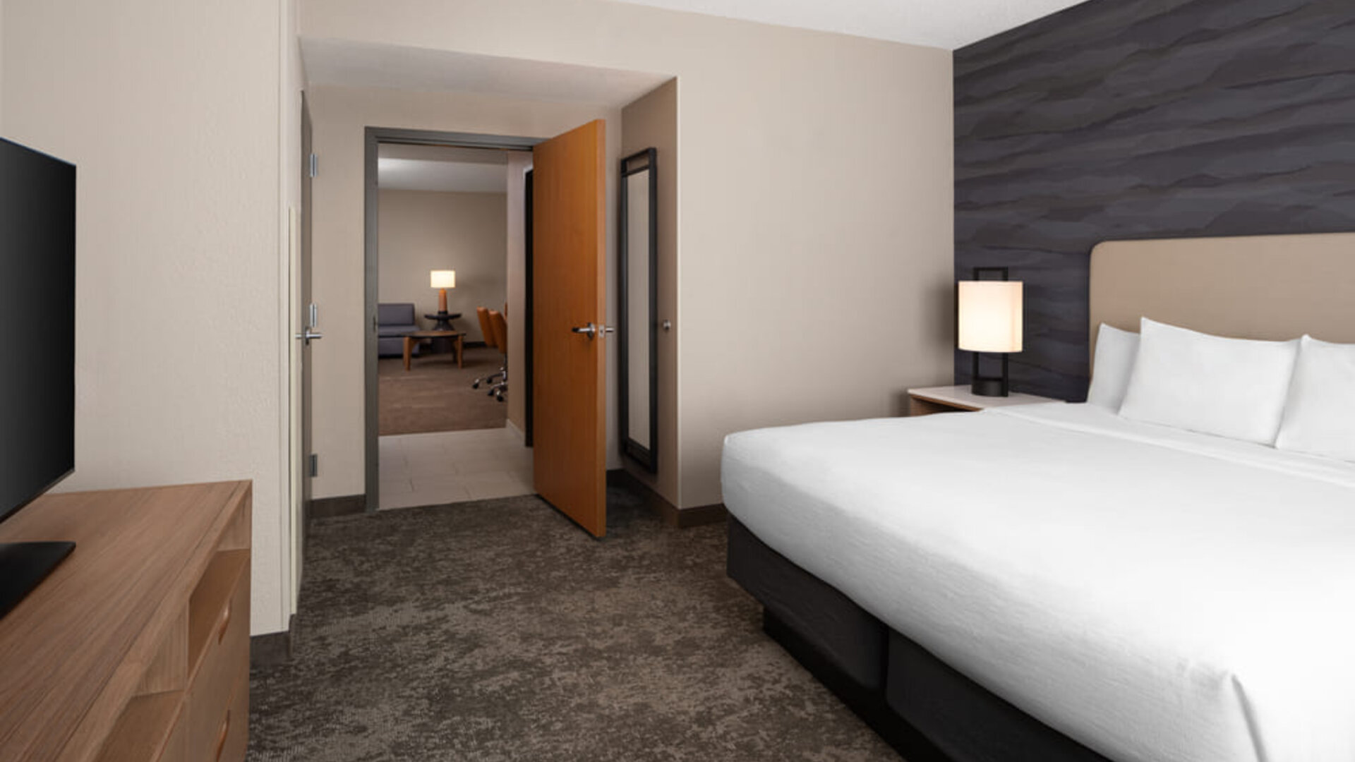 Private king bedroom featuring plush bedding, contemporary furnishings, and a separate suite layout for added comfort and privacy at Embassy Suites By Hilton Charleston Airport Convention Center.