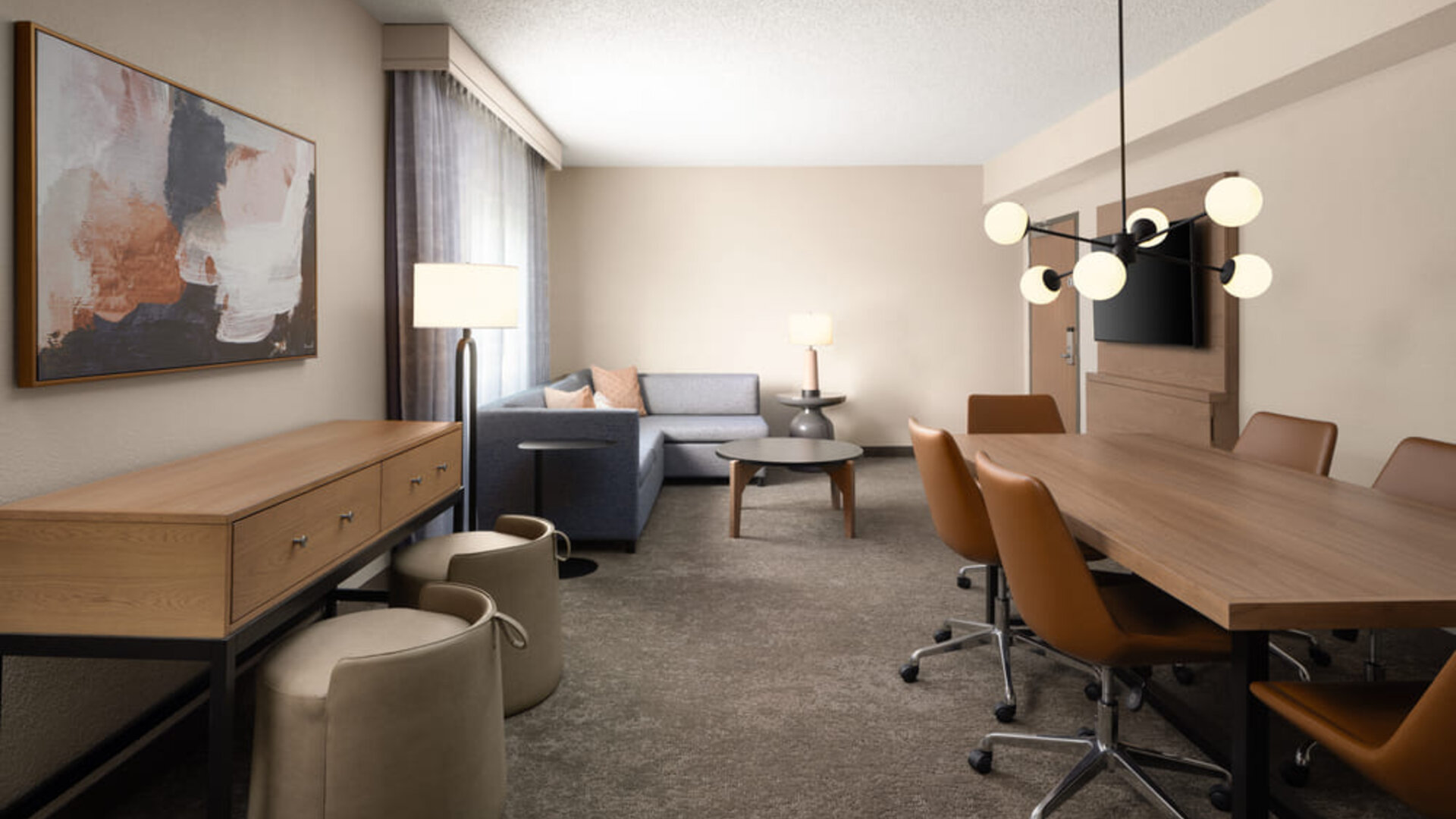Hospitality suite with conference-style dining table, lounge seating, and flexible space suitable for meetings, collaboration, or relaxation at Embassy Suites By Hilton Charleston Airport Convention Center.