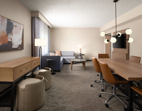 Hospitality suite with conference-style dining table, lounge seating, and flexible space suitable for meetings, collaboration, or relaxation at Embassy Suites By Hilton Charleston Airport Convention Center.