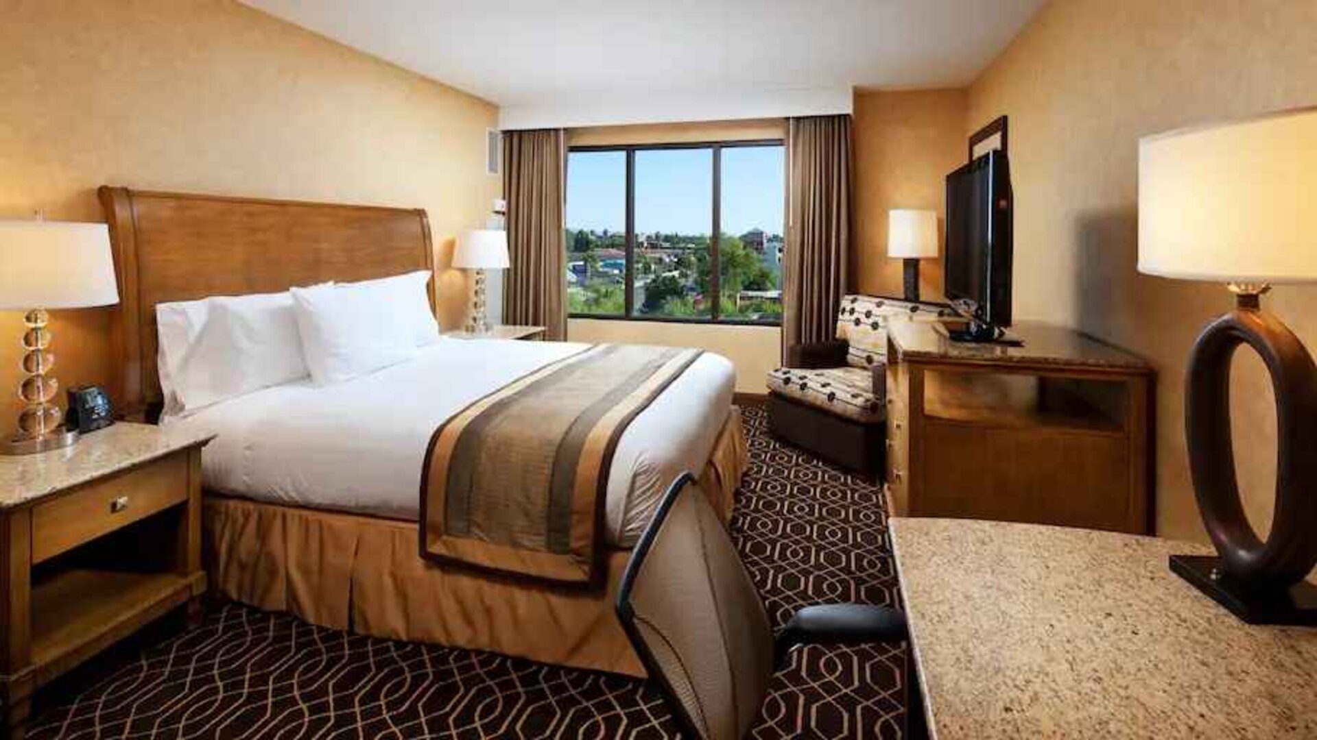 Bright king bedroom with window and working station at the DoubleTree Suites by Hilton Anaheim Resort-Convention Center.