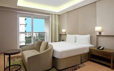 Bright king bedroom with sofa at the DoubleTree Suites by Hilton Bangalore.