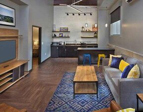 Living room with sofa and TV screen at the Tapestry By Hilton Scholar Morgantown, WV.
