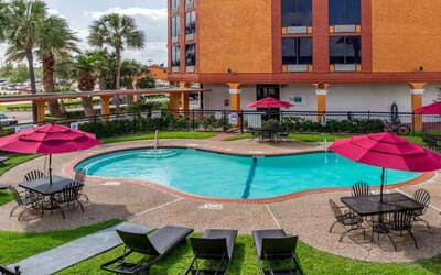 Large outdoor pool with seating area and sun umbrellas at Quality Inn Pasadena.