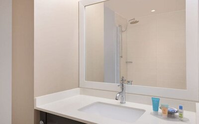 Spacious guest bathroom with shower at Courtyard By Marriott New York JFK Airport.