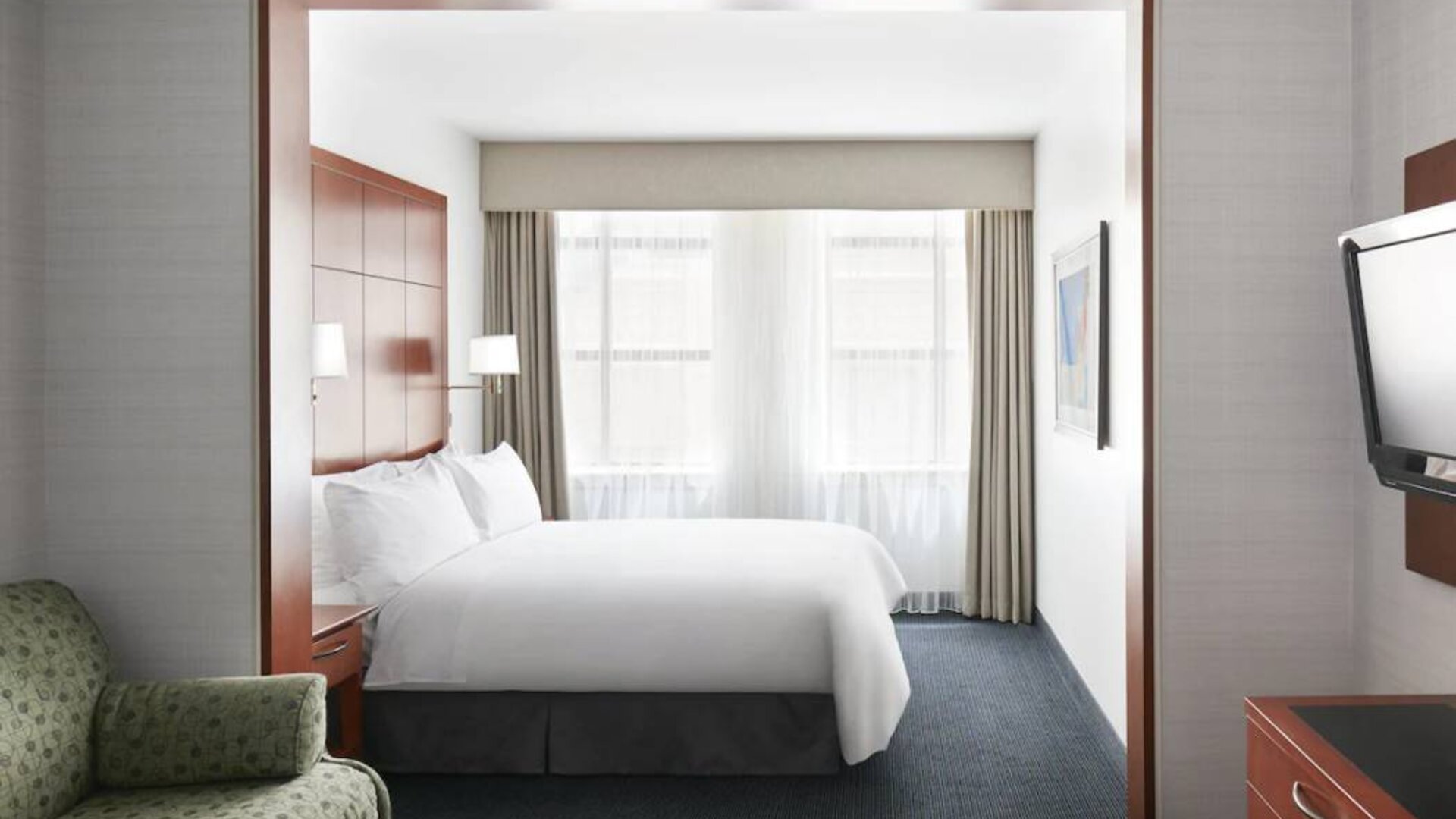 One of the Club Quarters Hotel Central Loop’s guest rooms, featuring bed, chair, and window.