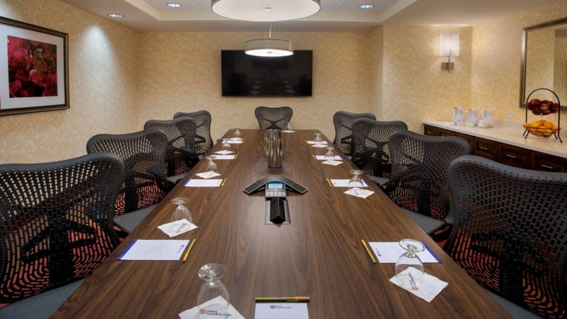 Meeting room in the Hilton Garden Inn Chicago Downtown Riverwalk, with long table, surrounding chairs and large TV.