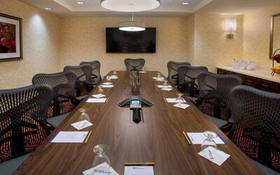 Meeting room in the Hilton Garden Inn Chicago Downtown Riverwalk, with long table, surrounding chairs and large TV.
