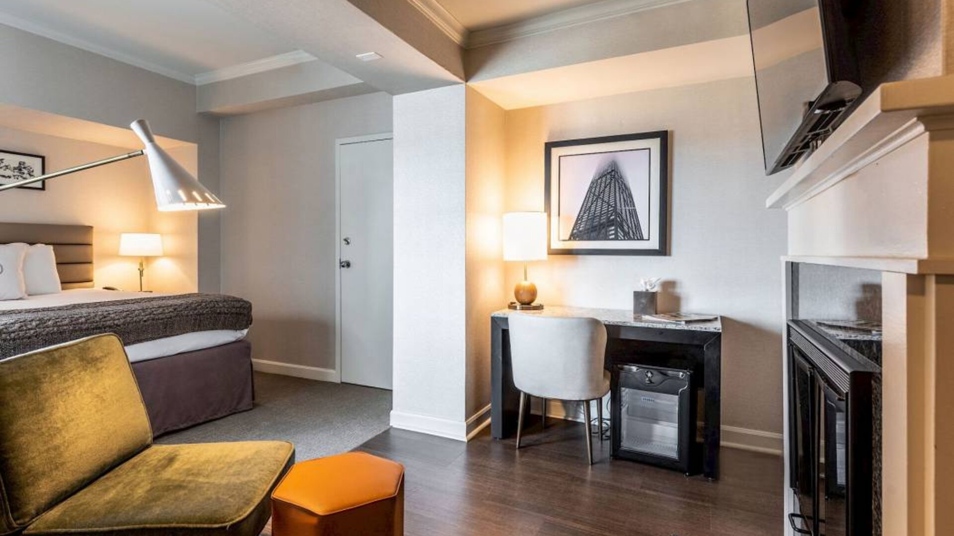 Guest room in Claridge House, featuring large bed, TV, and workspace desk and chair.