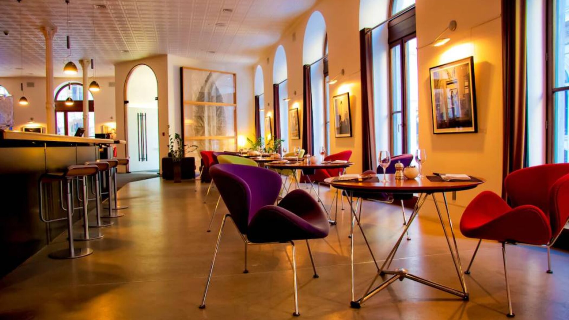 The hotel restaurant has a bar and small tables for diners to enjoy a refined breakfast experience.