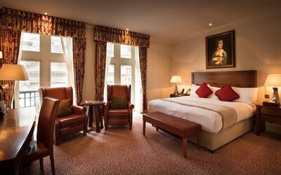 Deluxe king room at The Royal Horseguards Hotel, featuring numerous leather chairs, large windows, and a desk.