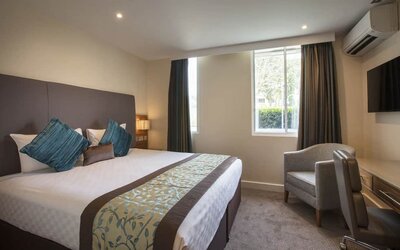 King-size bed with wall-mounted television in upper wall corner and a desk to work from.