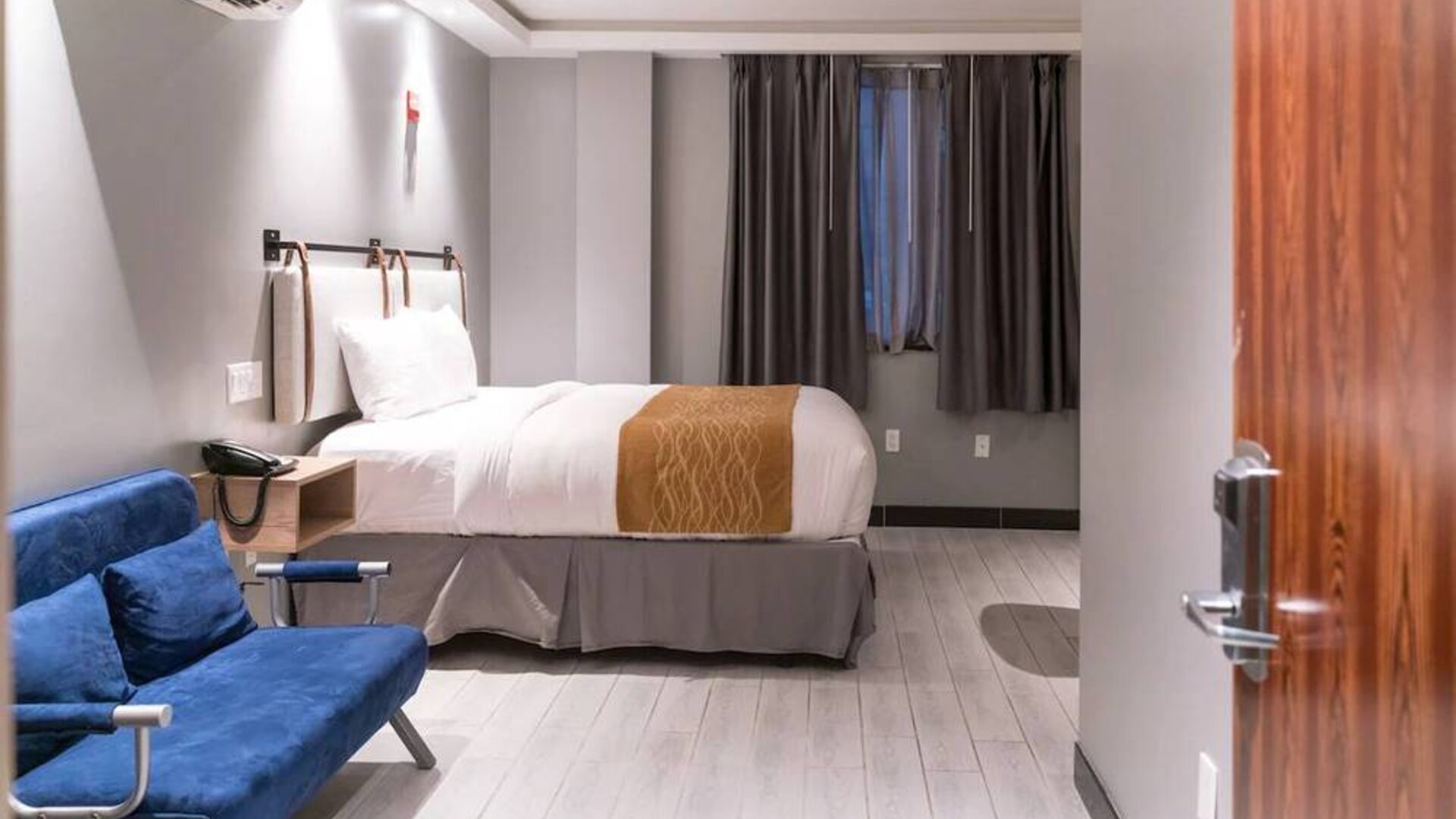 Double bedroom in the Madison LES Hotel, with window, telephone, and seating.