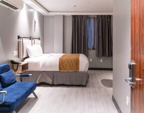 Double bedroom in the Madison LES Hotel, with window, telephone, and seating.