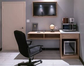 Workspace in a room at the Madison LES Hotel, including desk, chair, and microwave.