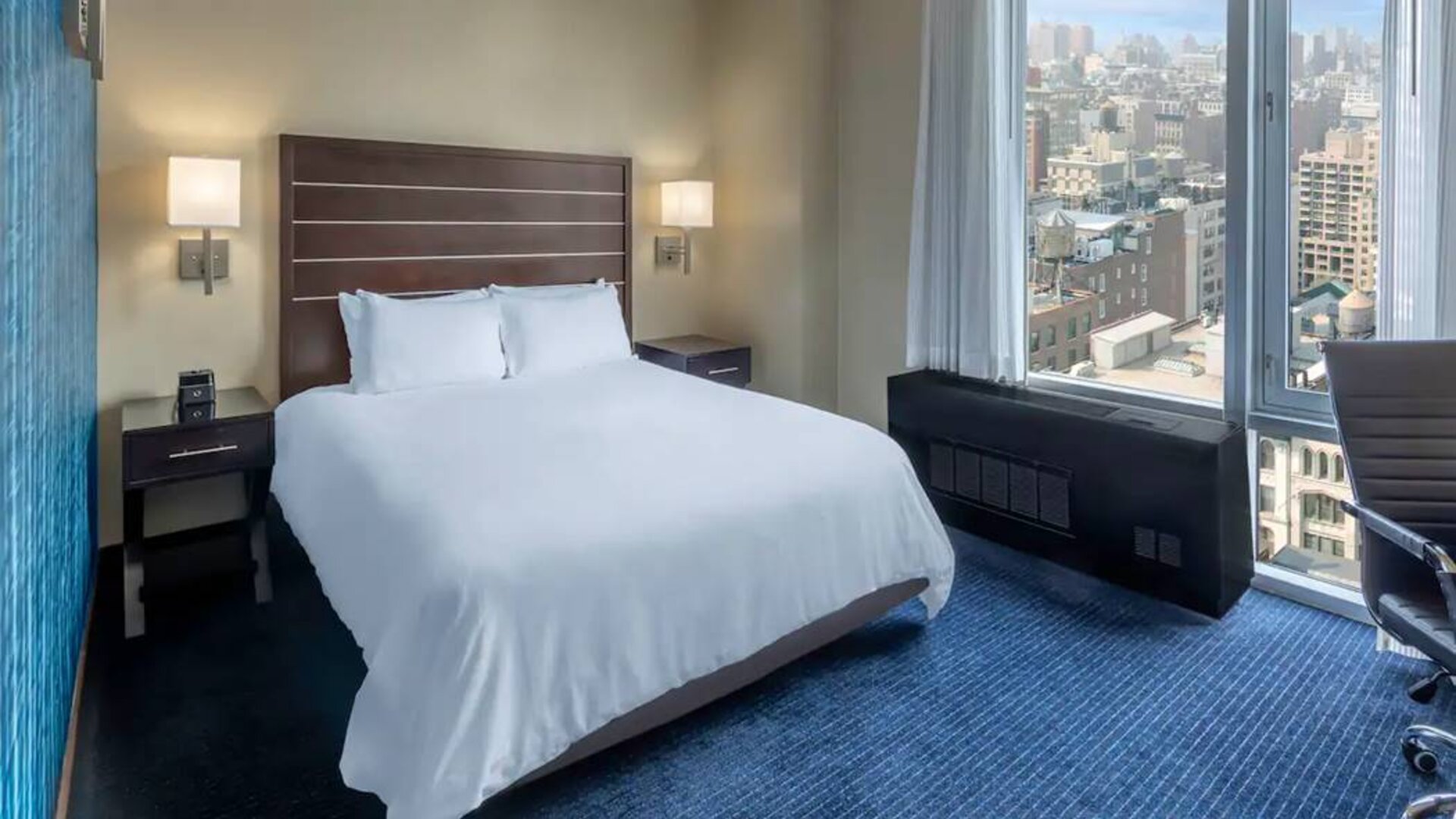 Guest room at the Hilton Fashion District, with double bed and view of the city.