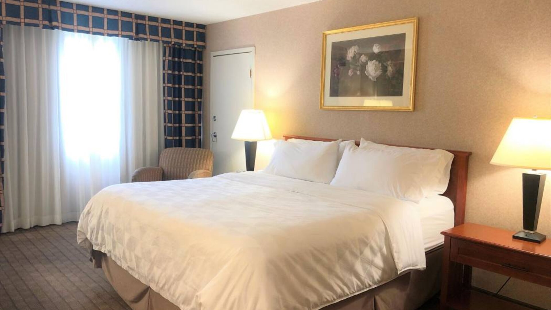 Double bed guest room in Holiday Inn Laval Montreal, with nearby chair and window.