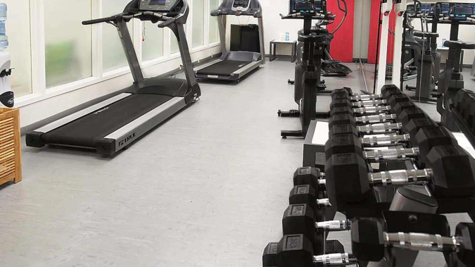 Hotel fitness center complete with rack of weights and various exercise machines.