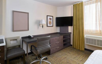 Workspace in a Candlewood Suites Times Square guest room, with desk, chair, TV, and window.