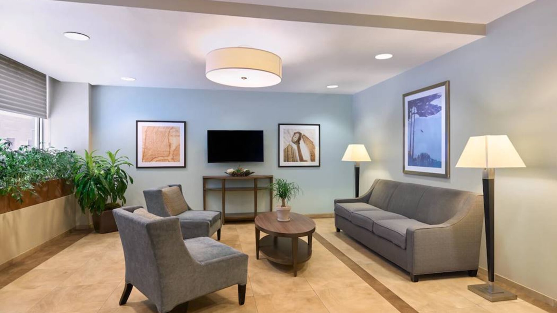The lounge in the Candlewood Suites Times Square lobby, with comfy chairs, sofa, table, and TV.