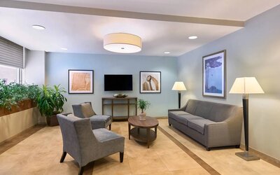 The lounge in the Candlewood Suites Times Square lobby, with comfy chairs, sofa, table, and TV.