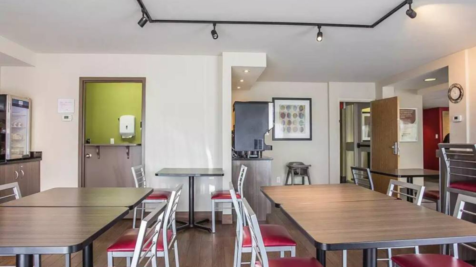 The hotel breakfast area has a hard floor and tables for two to four diners.