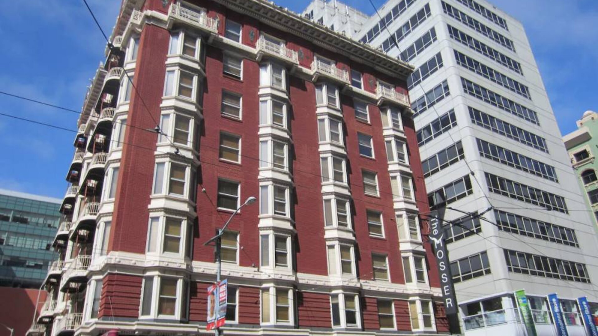 Exterior of the Mosser Hotel, with vertical sign and vibrant red brick hue.