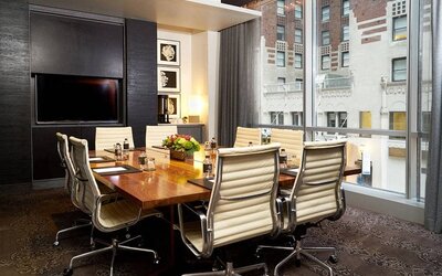 One of the hotel’s meeting rooms, with eight chairs around a long table, and a large TV screen.