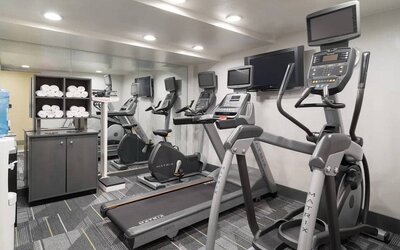Various exercise machines, towels, and TV in the hotel’s fitness center.
