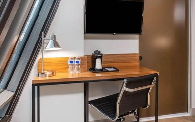 An in-room workspace at La Quinta Times Square South, with desk, chair, lamp, and TV.