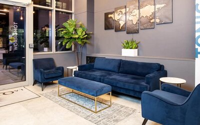 The lounge located in La Quinta Times Square South’s lobby, with comfy seating and potted plants.