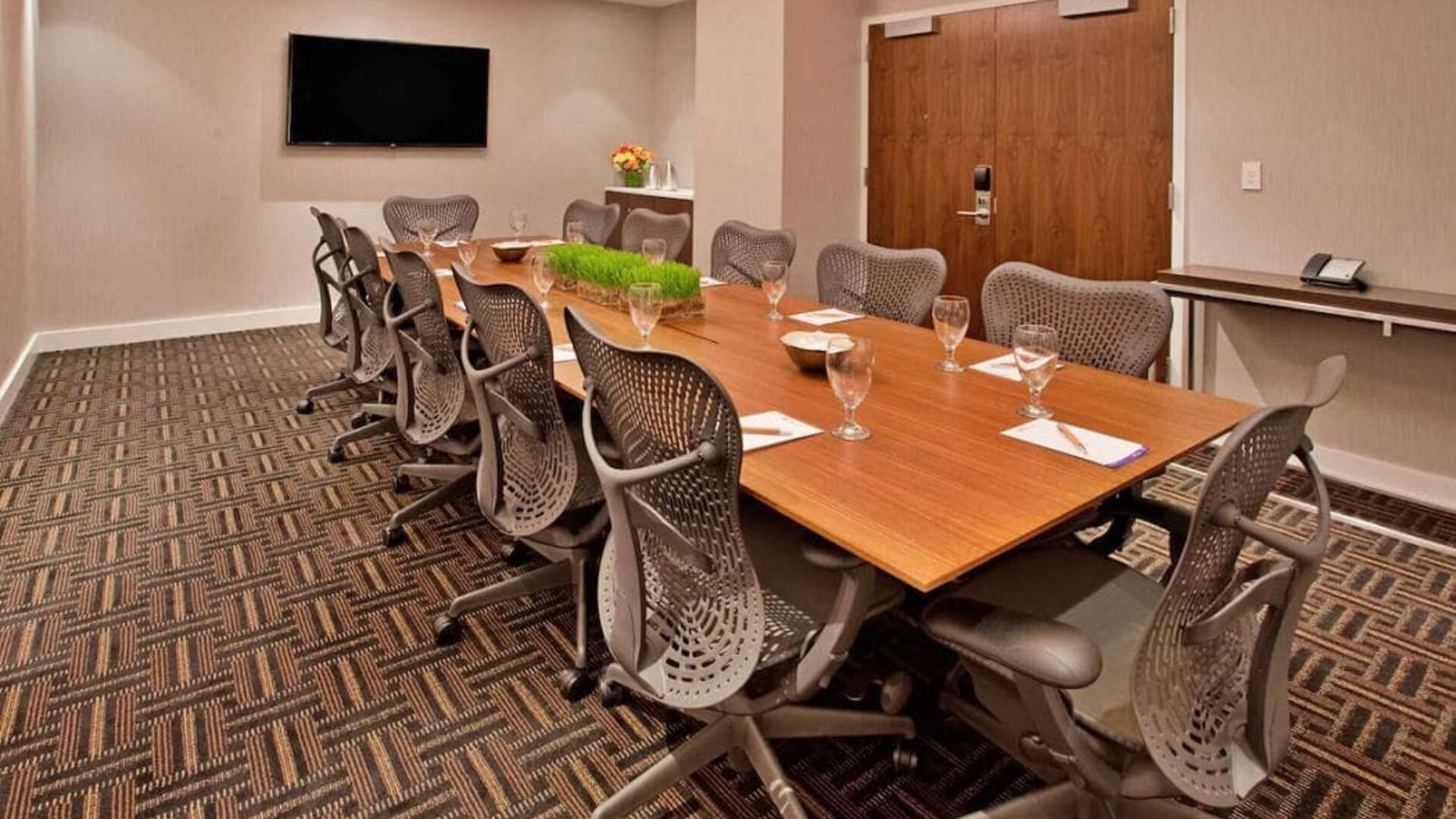 Meeting room with long wooden table and a dozen swivel chairs around it.