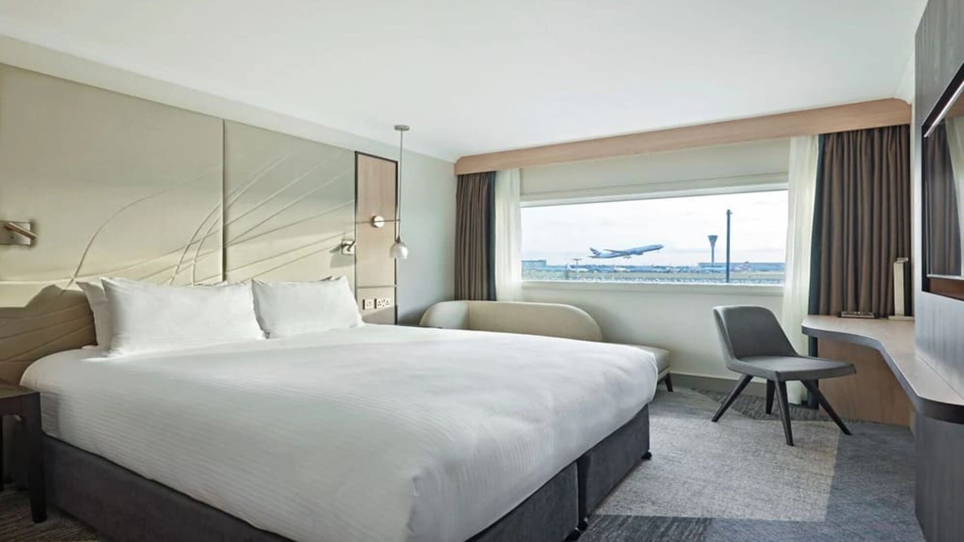 King bedroom with work desk and natural light at Hyatt Place London Heathrow Airport.