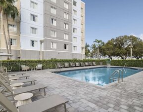 Loungers beside outdoor pool at Homewood Suites By Hilton Miami Airport-Blue Lagoon.