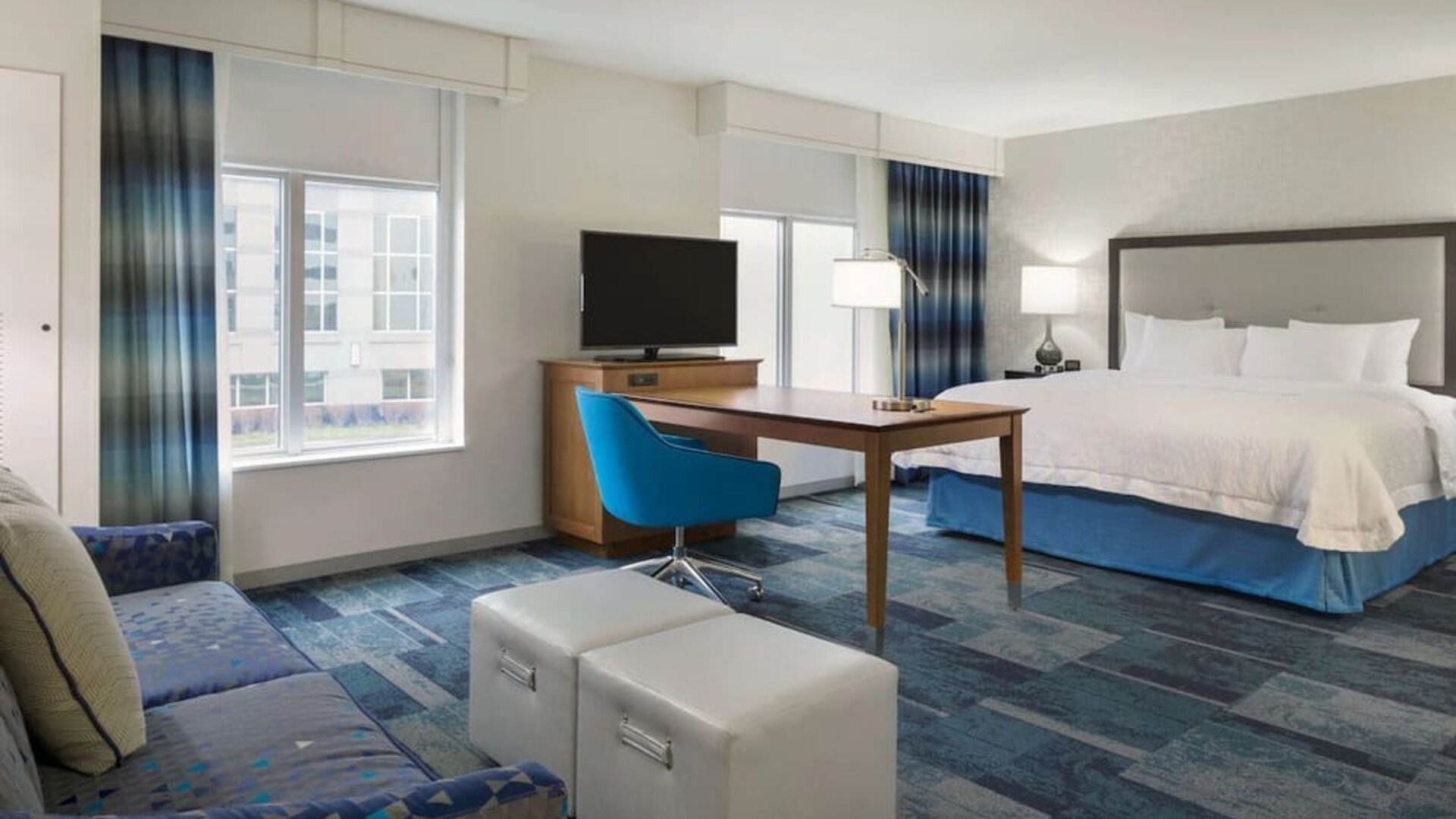 Spacious delux king bed with lounge area at Hampton Inn & Suites Rosemont Chicago O'Hare.