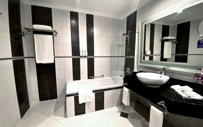 Guest bathroom with shower and bath at Millennium Central Doha.