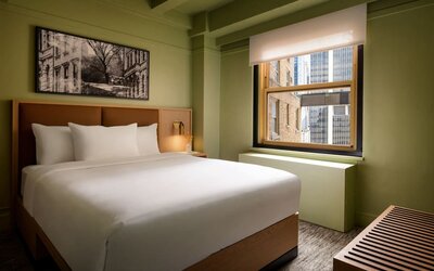 Guest room with natural light, city views, and minimalist modern furnishings at Row NYC.
