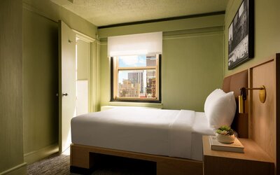 Cozy guest room with natural light, city views, and minimalist modern furnishings at Row NYC.