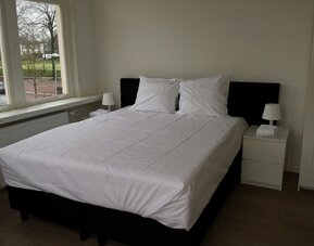 Bright king bedroom featuring large windows, comfortable bedding, and minimalist décor at Hotel Chao 24/7.