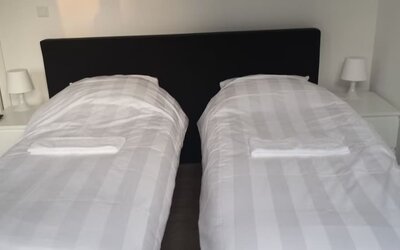Twin guest room with two single beds, bedside tables, and crisp white linens at Hotel Chao 24/7.
