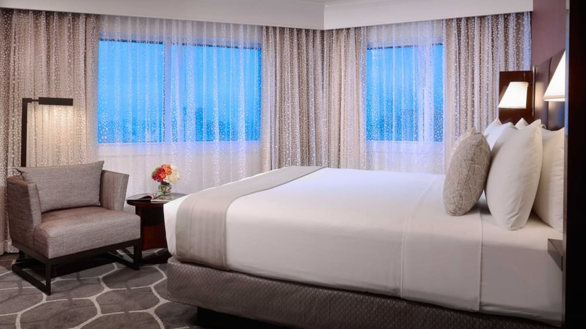 Royal Sonesta Houston Galleria king bed guest room, including windows, armchair, and coffee table.
