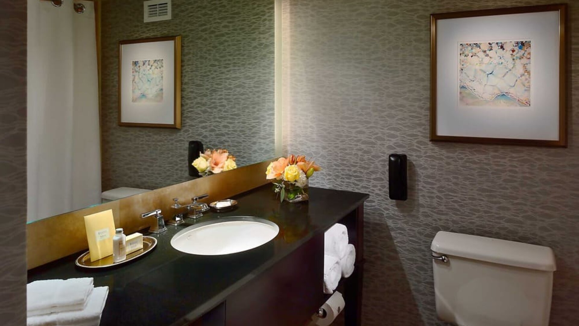 Guest bathroom in Royal Sonesta Houston Galleria, with lavatory, sink, and wide mirror.