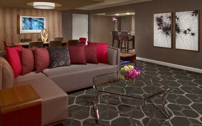 Royal Sonesta Houston Galleria workspace, featuring corner sofa and coffee table, plus long table surrounded by chairs.