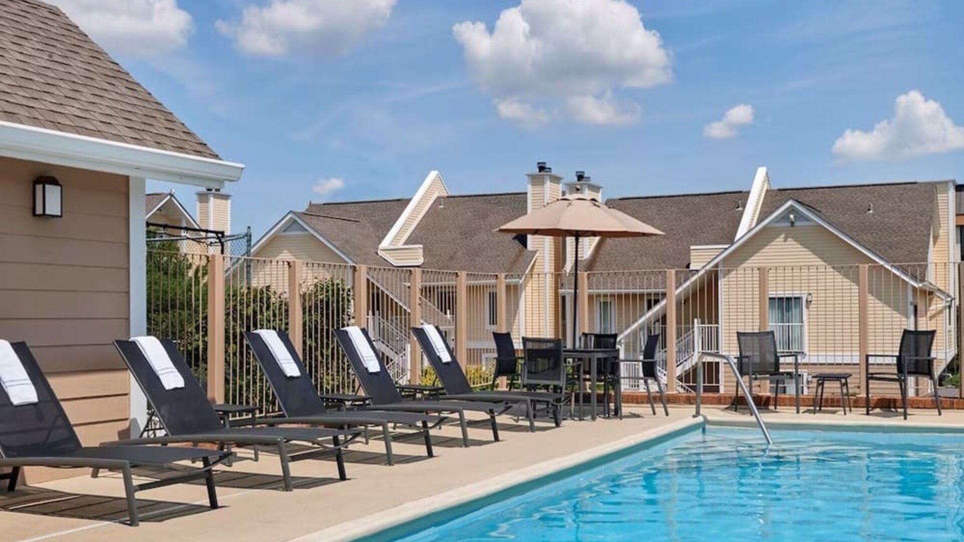 Sonesta ES Suites Tucson’s outdoor pool has a row of sun loungers, plus tables and chairs, by the side.