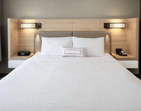 Sonesta Select Nashville Airport Suites deluxe king bed room, featuring bedside lamps and telephone.