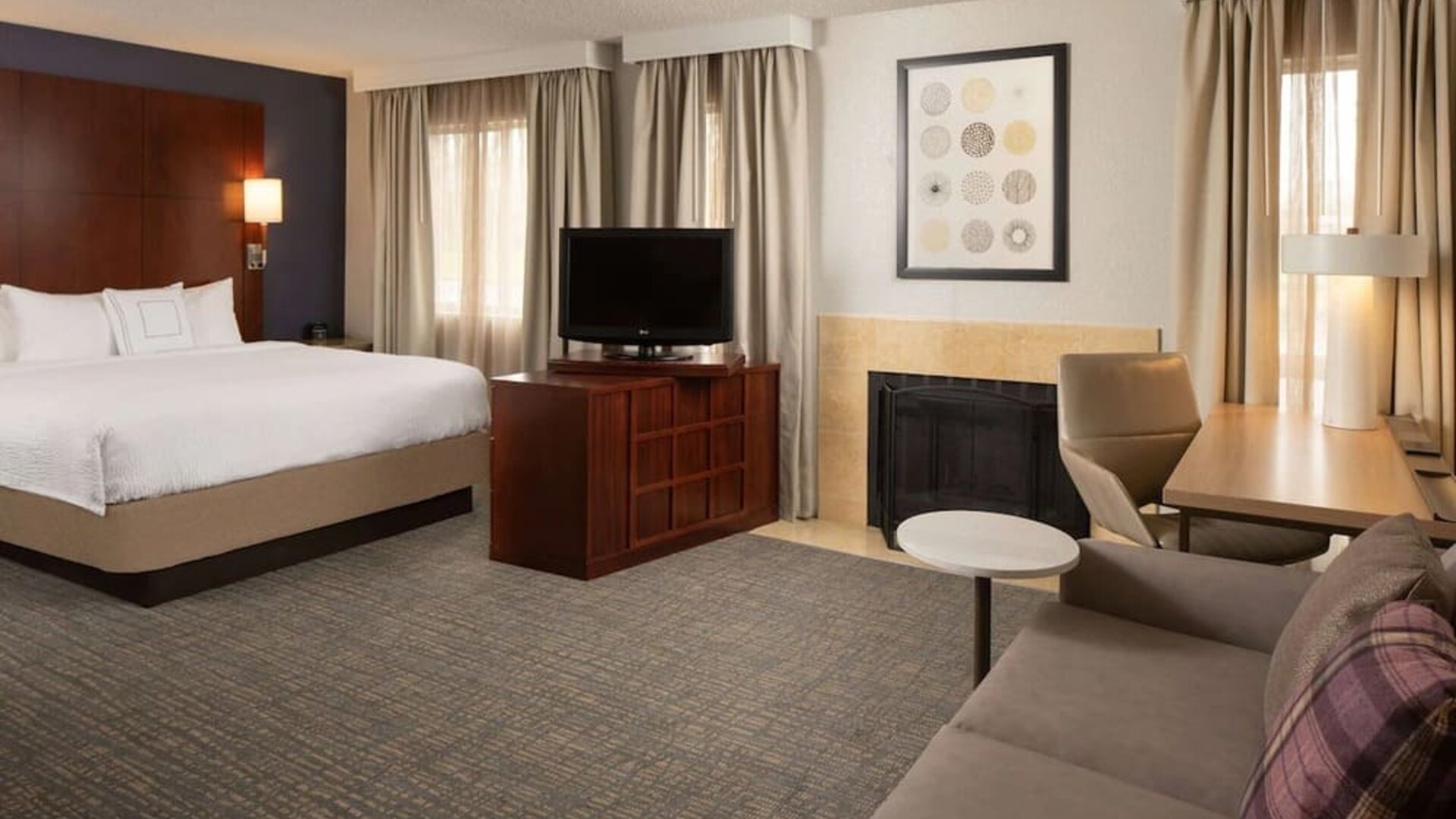 Sonesta ES Suites Nashville Brentwood king bed guest room, furnished with sofa, desk, and TV.