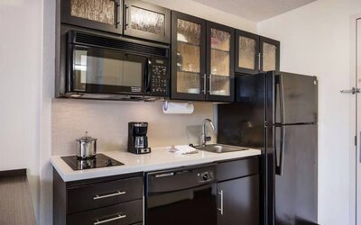 Sonesta Simply Suites Arlington guest room kitchen area, including fridge-freezer, oven, hob, and microwave.