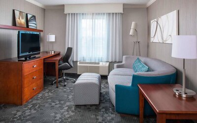 Sonesta Select Boston Lowell Chelmsford guest room lounge, furnished with sofa, chair, and TV.