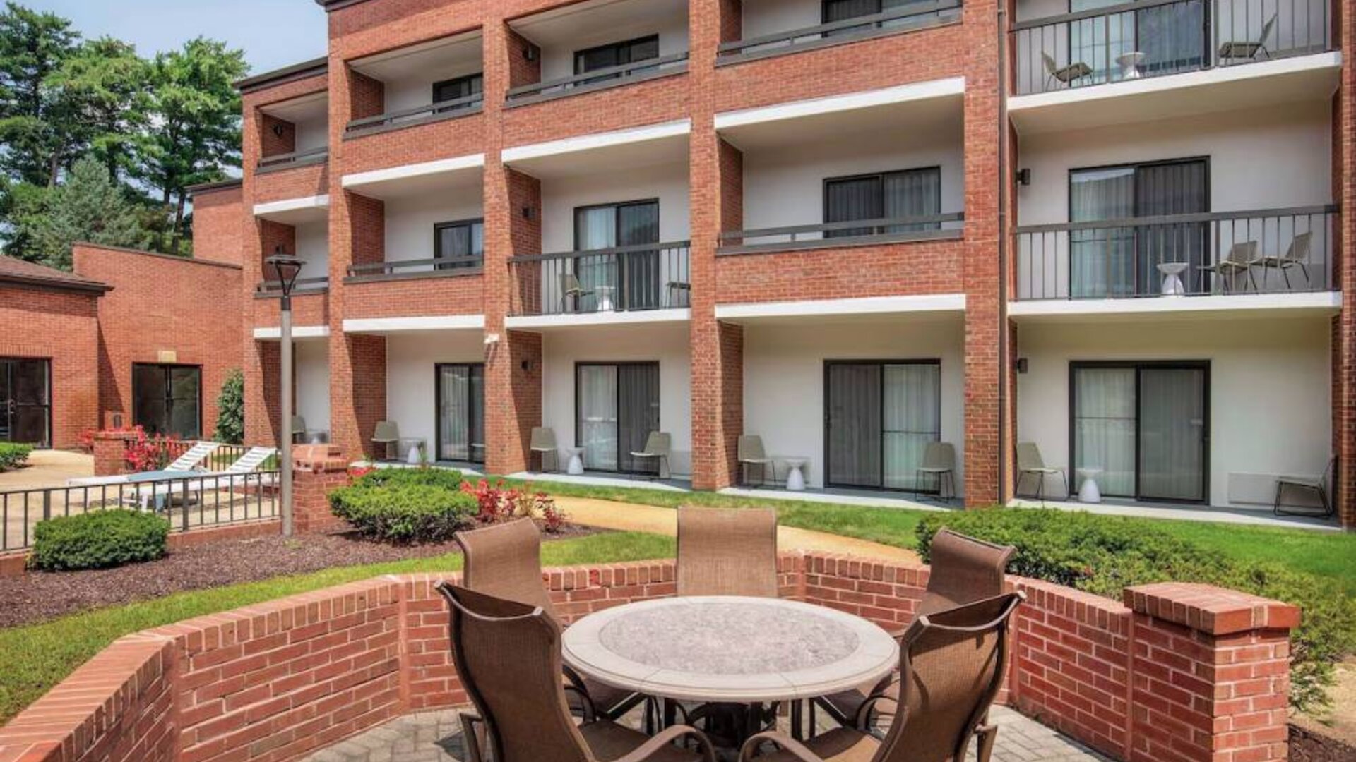 The hotel patio is close to the rooms, and has a circular table surrounded by a quintet of chairs.